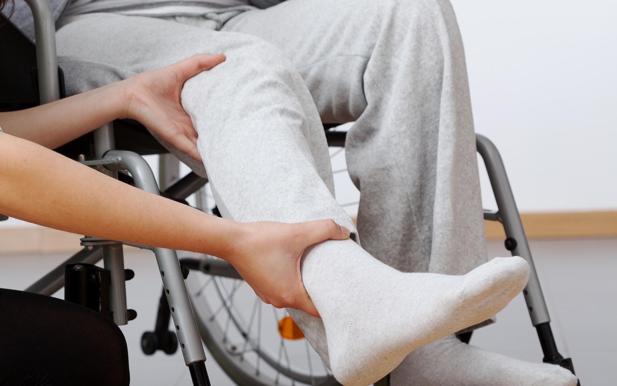 Caregiver tending to the foot of a senior in a wheelchair, providing attentive and compassionate care