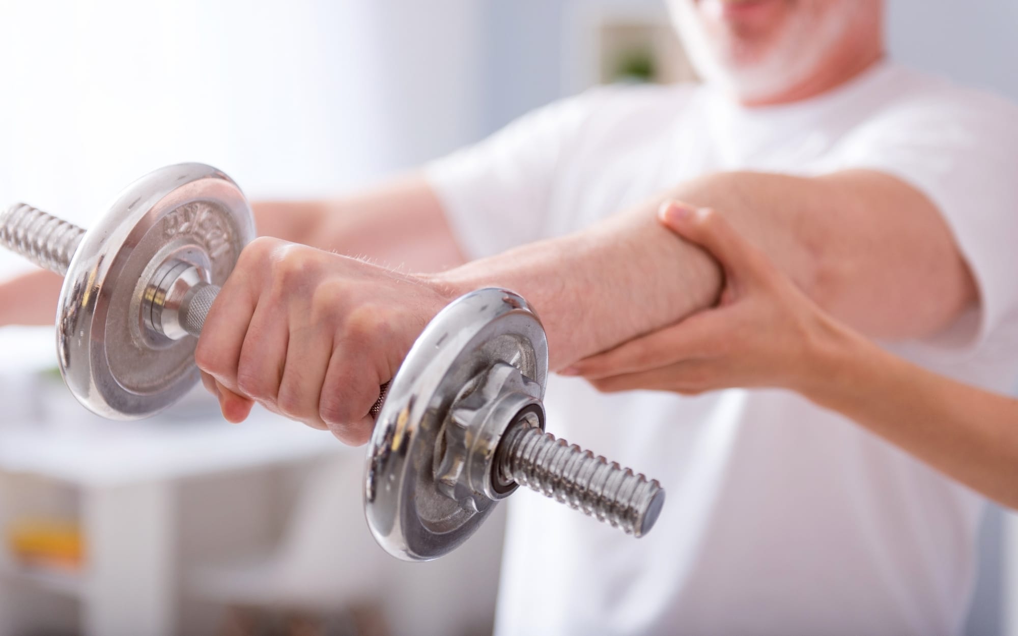 Senior using a dumbbell during a home therapy session to improve strength and mobility