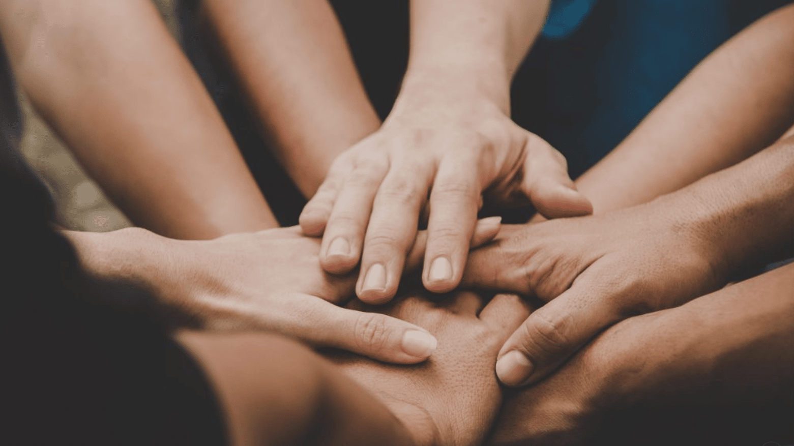 Multiple hands gently holding together, symbolizing unity, support, and compassionate care