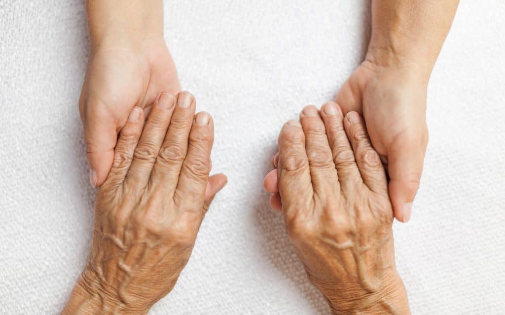 Close-up of caregiver’s hand gently holding an elder’s hand, symbolizing care and connection
