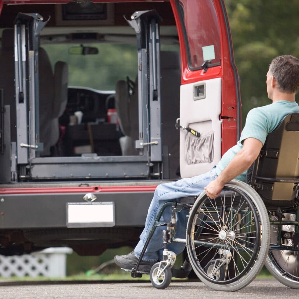 Senior in a wheelchair positioned beside a car, preparing to board independently