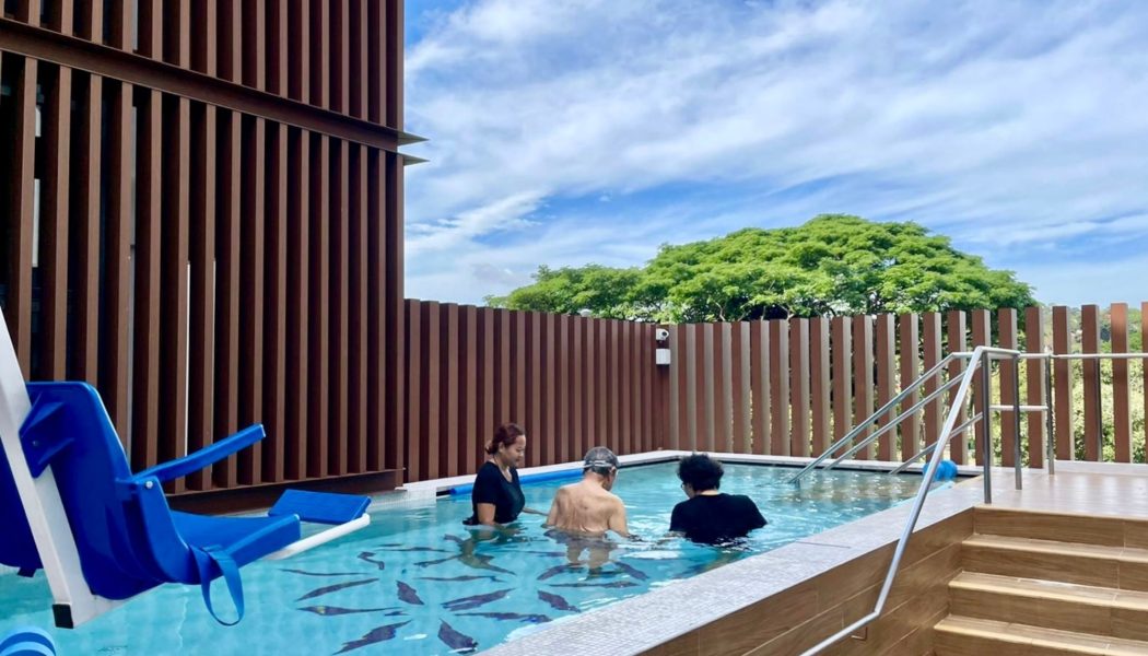 Senior engaging in hydrotherapy with therapist support in a warm, therapeutic pool